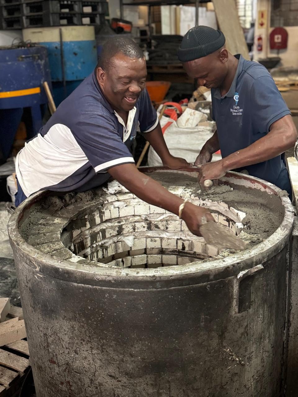 Two Cross Refractory bricklayers building a circular firebrick lining